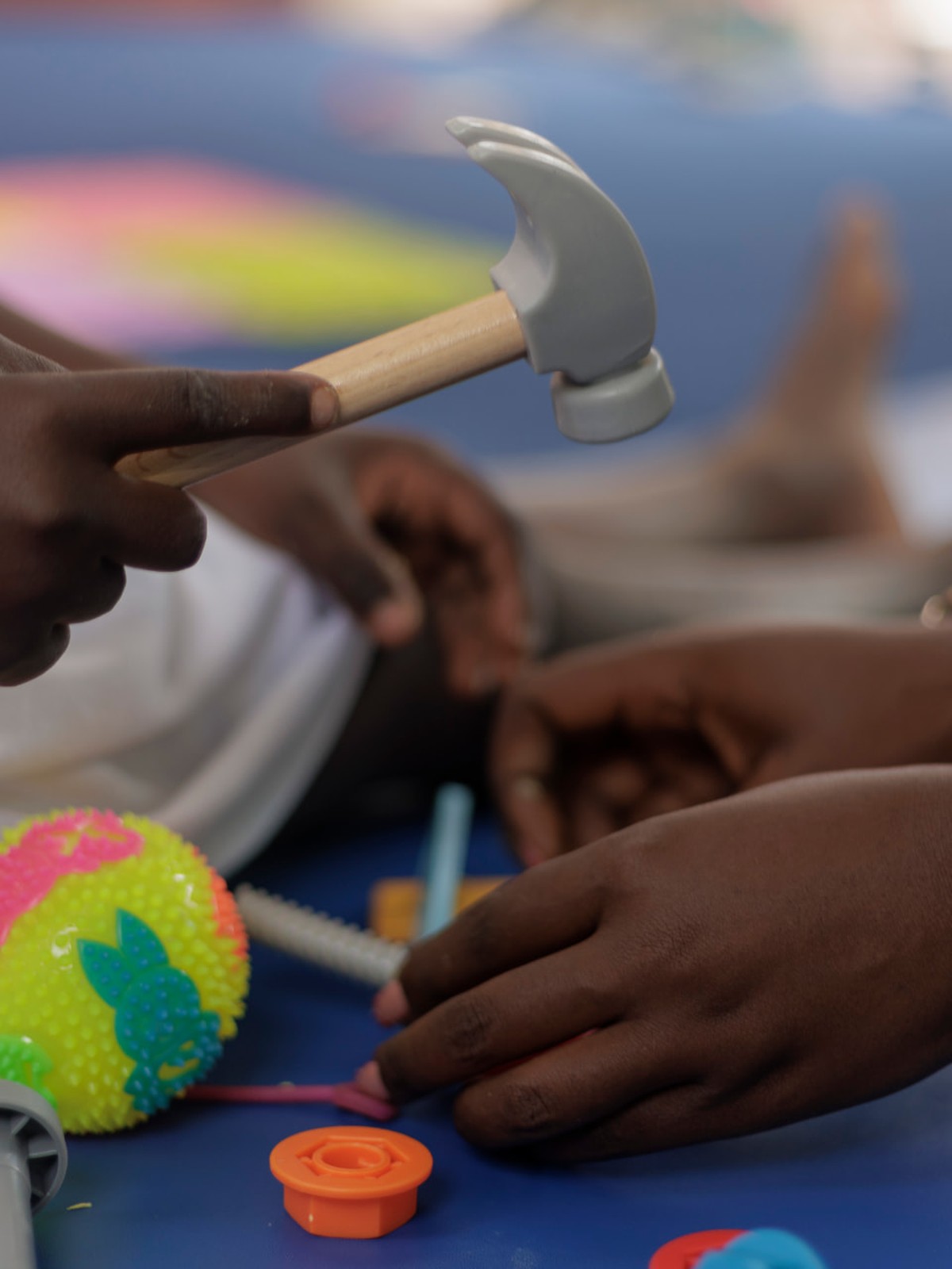 A child practises fine-motor skills by tapping colourful pegs with a toy hammer during an occupational therapy session at Siloam