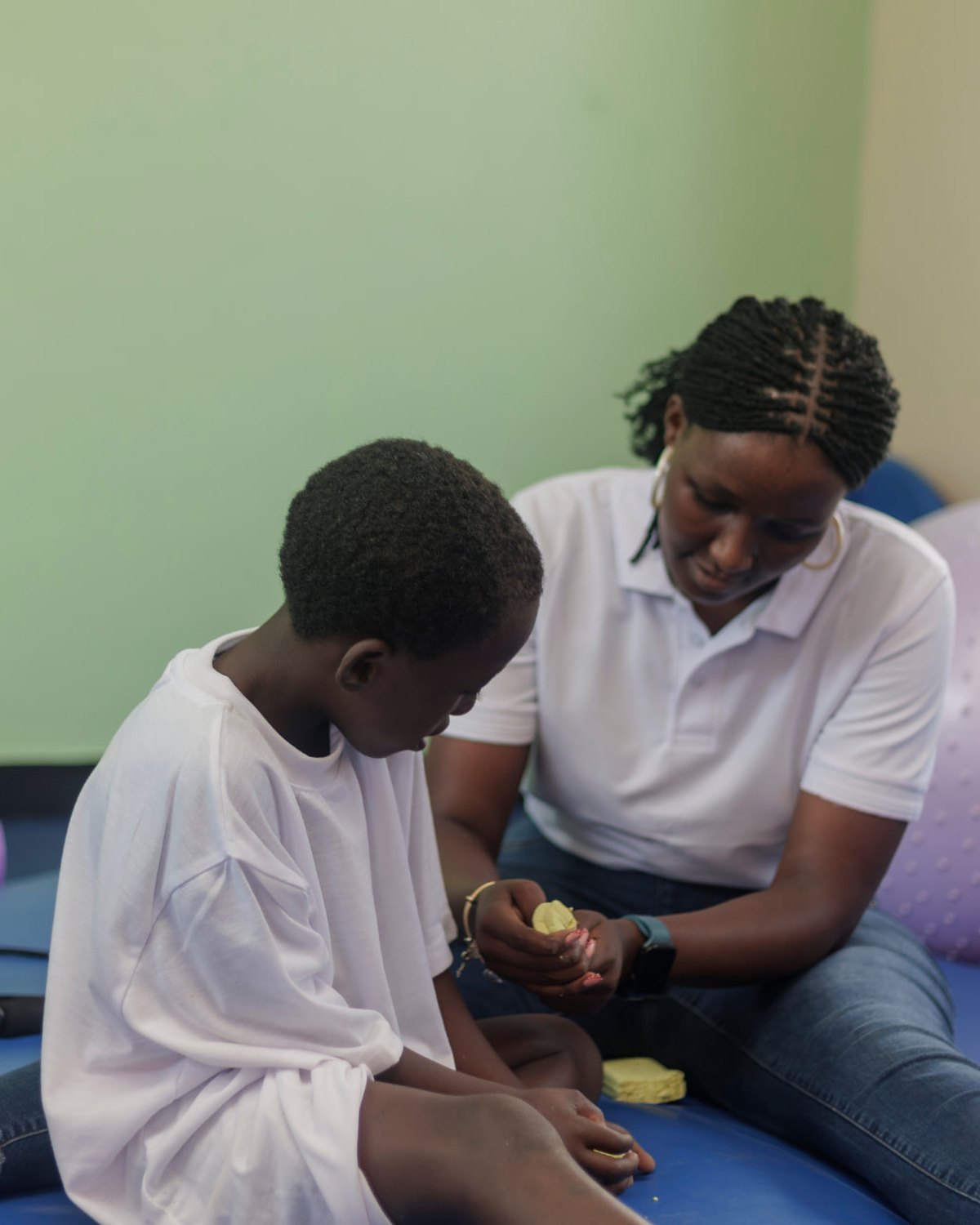 A Siloam therapist and a boy shaping modelling clay together during an occupational therapy session at the Centre