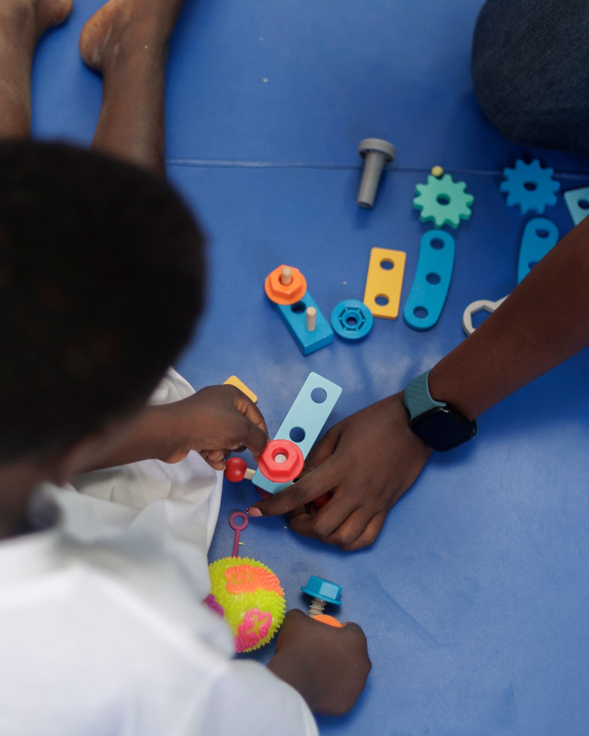 A therapist and a child at Siloam Rehabilitation Centre building with colourful wooden construction toys during an occupational therapy session